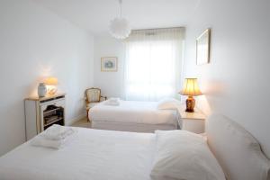 a white bedroom with two beds and a window at Appartement 2 chambres Chartrons in Bordeaux