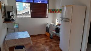 una pequeña cocina con nevera y mesa en Regiane Beach Pousada Hostel, en João Pessoa