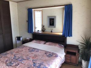 Schlafzimmer mit einem Bett mit blauen Vorhängen und einem Fenster in der Unterkunft Kamogawa - House - Vacation STAY 9977 in Kamogawa