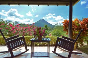 two chairs and a table on a patio with a mountain at Arenal Manoa Resort & Hot Springs in Fortuna
