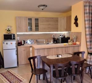 a kitchen with a table and a white refrigerator at Апартамент Allegri Padrini Комплекс Вели Хилс in Velingrad