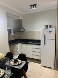 a kitchen with a white refrigerator and a table with chairs at Apartamento Borges Gramado in Gramado