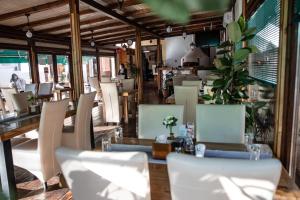 ein Restaurant mit weißen Stühlen sowie einem Tisch, Tischen und Stühlen in der Unterkunft Gran Gala in Baia Mare