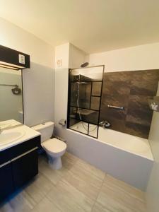 a bathroom with a toilet and a tub and a sink at Le Belvédère - GÎTES MARCK in Turckheim