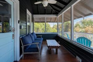 a porch with blue chairs and a table and a ceiling fan at 306 E Arctic Ave. in Folly Beach