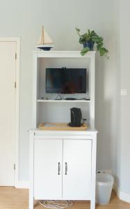 a white cabinet with a tv on top of it at De Rode Beuk in Wassenaar