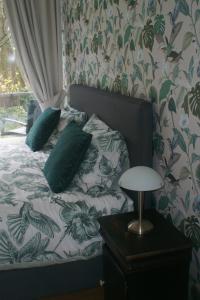 a bed with green pillows and a table with a lamp at De Rode Beuk in Wassenaar