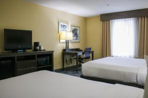a hotel room with two beds and a desk with a television at Country Inn & Suites by Radisson, Richmond West at I-64, VA in Richmond