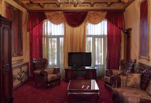 a living room with a couch and a tv and curtains at Alexandrapol Palace Hotel in Gyumri