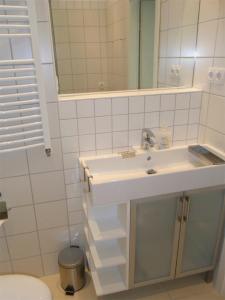 a white bathroom with a sink and a mirror at City Lodging Apartments in Berlin