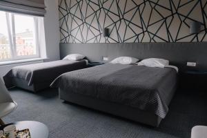 a bedroom with two beds and a geometric wall at Bohema in Telšiai