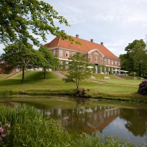 une grande maison avec un étang en face de celle-ci dans l'établissement Hindsgavl Slot, à Middelfart