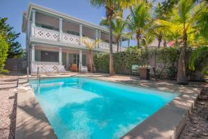 a swimming pool in front of a house with palm trees at Villa Aquamarine, 2 bedroom beach house and private pool, Orient beach! in Orient Bay