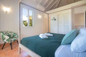 a bedroom with a bed with a chair and a window at Villa Aquamarine, 2 bedroom beach house and private pool, Orient beach! in Orient Bay +27 photos