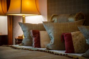a pile of pillows on a bed with a lamp at Kilmeny in Ballygrant