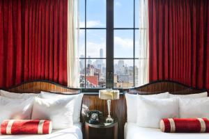 a bedroom with two beds with red curtains and a window at Walker Hotel Greenwich Village in New York