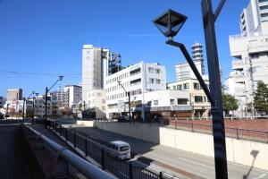 a bus driving down a city street with tall buildings at Compass in Nagano