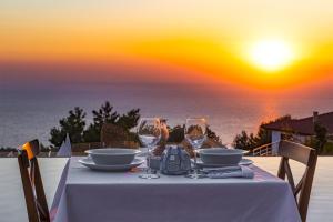 a table with wine glasses and a view of the ocean at Highclere Hotel and Spa in Faralya
