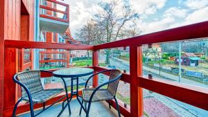 a balcony with a table and two chairs and a window at Apartament Spokojny Holiday Mountain Residence - 5D Apartamenty in Świeradów-Zdrój