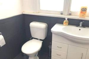 a bathroom with a white toilet and a sink at Modern Charming Miners’ Cottage +Free Internet in Broken Hill
