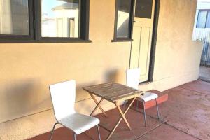 three chairs and a wooden table and a table and chairs at Modern Charming Miners’ Cottage +Free Internet in Broken Hill