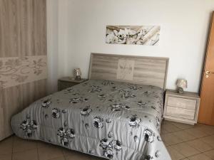 una camera da letto con un letto con un piumone grigio e bianco di Luxury Affitti brevi a Marconia