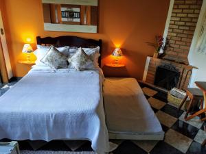 a bedroom with a bed with two lamps and a fireplace at Pousada Amor Perfeito in Visconde De Maua