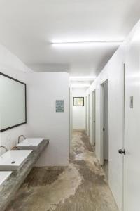 a white bathroom with two sinks and a mirror at Sunlit Hostel in General Luna