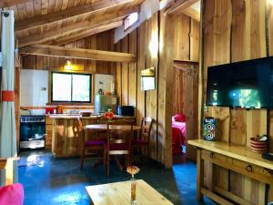 sala de estar con mesa y cocina con paredes de madera. en Cabañas Peumayén Neltume, en Neltume
