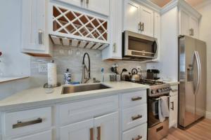 cocina con armarios blancos, fregadero y nevera en 1000#4 Modern Beach Home, Steps from Sand w/AC! en Newport Beach