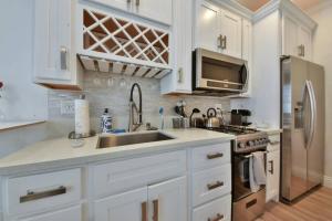 a kitchen with white cabinets and a sink and a refrigerator at 1000#4 Modern Beach Home, Steps from Sand w/AC! in Newport Beach