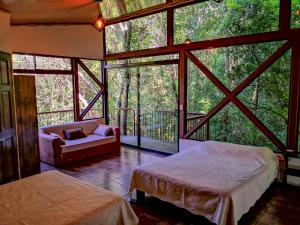 una camera con due letti e un divano in una stanza con finestre di Quality Cabins Monteverde a Monteverde Costa Rica