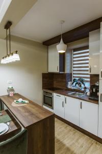 cocina con armarios blancos y encimera de madera en Vively Lux Apartment en Subotica