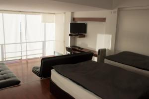 Hotel Onkel Inn Torres de Copacabana في كوباكابانا: غرفة نوم بسرير واريكة وتلفزيون