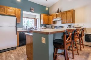 Una cocina con gabinetes de madera y un refrigerador blanco. en Helios S # 5, en Mammoth Lakes