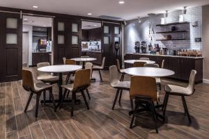a restaurant with tables and chairs and a kitchen at Residence Inn by Marriott Charlotte Steele Creek in Charlotte