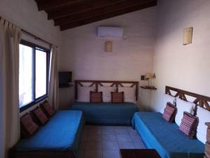 Habitación con 2 camas azules y ventana. en Fincas del Huacle en Nono