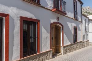 biały budynek z drewnianymi drzwiami na ulicy w obiekcie Casa La Aldaba w mieście Montejaque