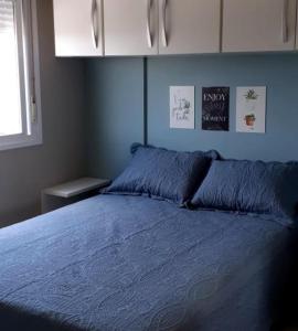 1 dormitorio con cama con sábanas azules y ventana en Apartamento aconchegante com vista para o vale dos vinhedos, en Bento Gonçalves