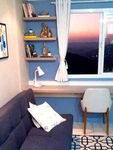 uma sala de estar com um sofá azul e uma janela em Apartamento aconchegante com vista para o vale dos vinhedos em Bento Gonçalves
