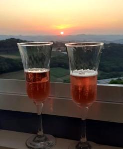 dos vasos de cerveza sentados en el alféizar de la ventana con la puesta de sol en Apartamento aconchegante com vista para o vale dos vinhedos, en Bento Gonçalves