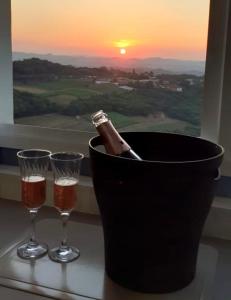 Una botella de champán en un cubo junto a dos copas. en Apartamento aconchegante com vista para o vale dos vinhedos, en Bento Gonçalves