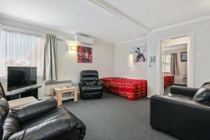 uma sala de estar com mobiliário de couro preto e uma televisão de ecrã plano em Arcadia Motel em Christchurch