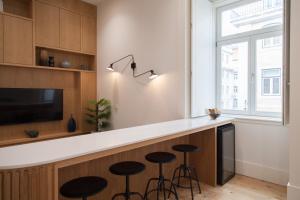 a kitchen with a bar with stools and a tv at FLH Praça Comércio Tropical Flat in Lisbon