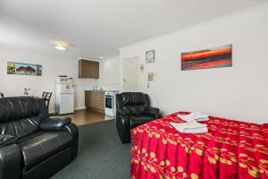 uma sala de estar com duas cadeiras de couro e um cobertor vermelho em Arcadia Motel em Christchurch