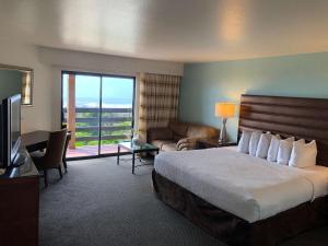 a hotel room with a bed and a couch and a television at SureStay Plus Hotel by Best Western Gold Beach in Gold Beach