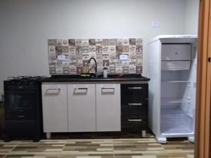 cocina con fregadero y nevera abierta en Kitnet contêiner climatizada, en Ubatuba