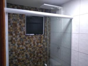 uma casa de banho com um chuveiro e uma televisão na parede em Kitnet contêiner climatizada em Ubatuba