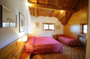 a bedroom with two beds in a room with wooden ceilings at Hotel 2 Camini in Baselga di Pinè