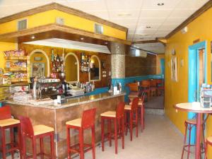 a restaurant with a bar with red stools at Hotel Vimar in Sanxenxo